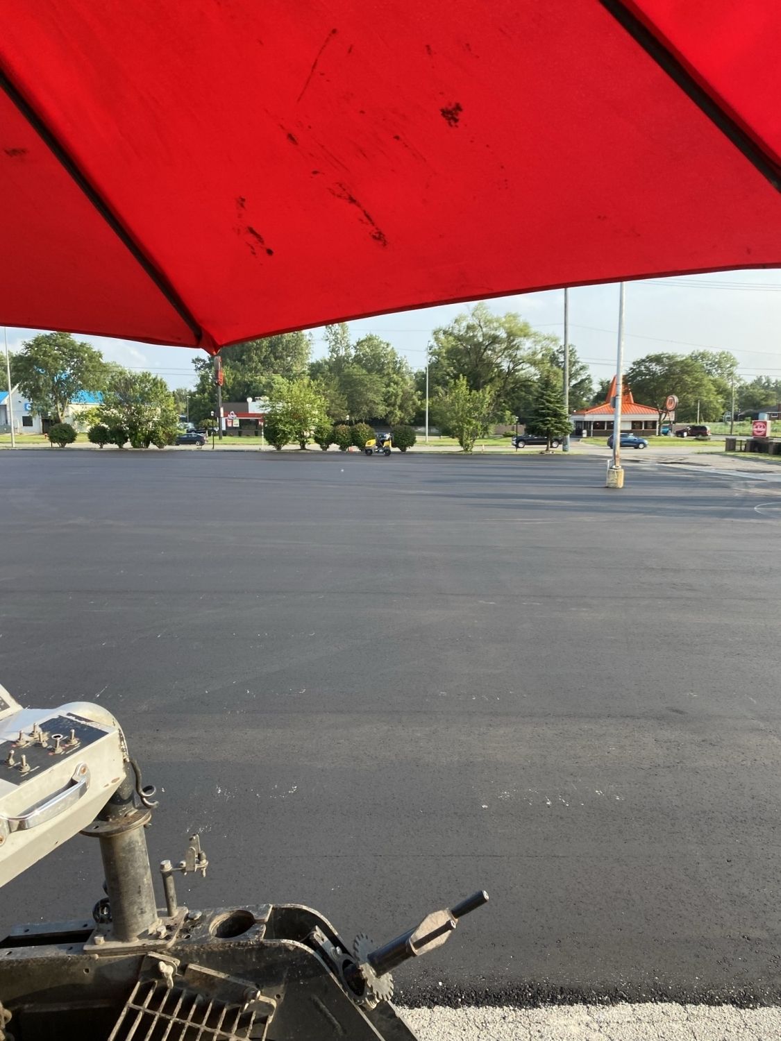 A red umbrella is sitting in a parking lot