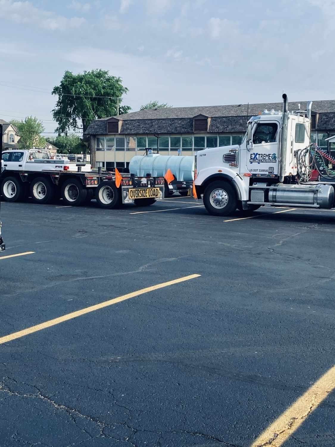 A row of semi trucks are parked in a parking lot.