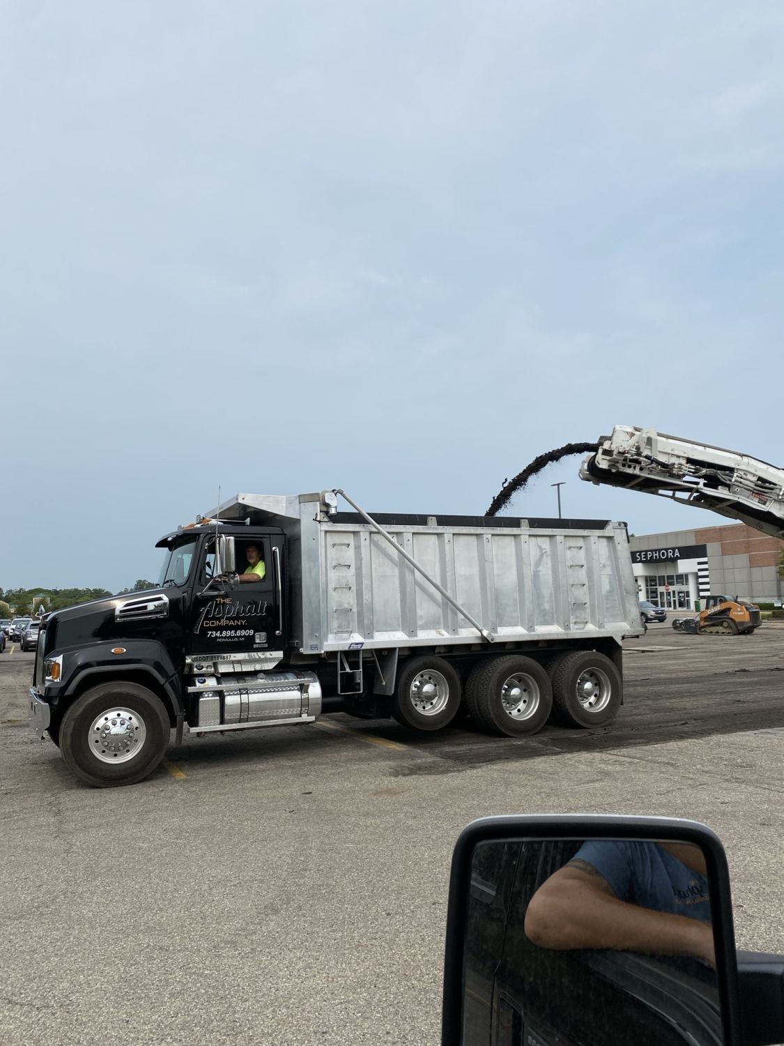 A dump truck is parked in a parking lot with a crane attached to it.