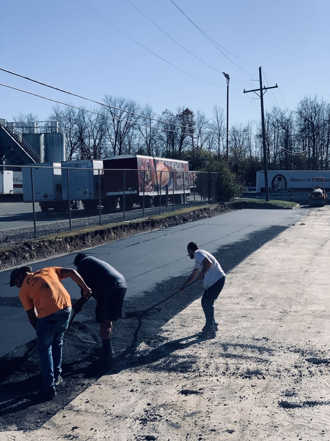 Three men are working on a road with a truck in the background