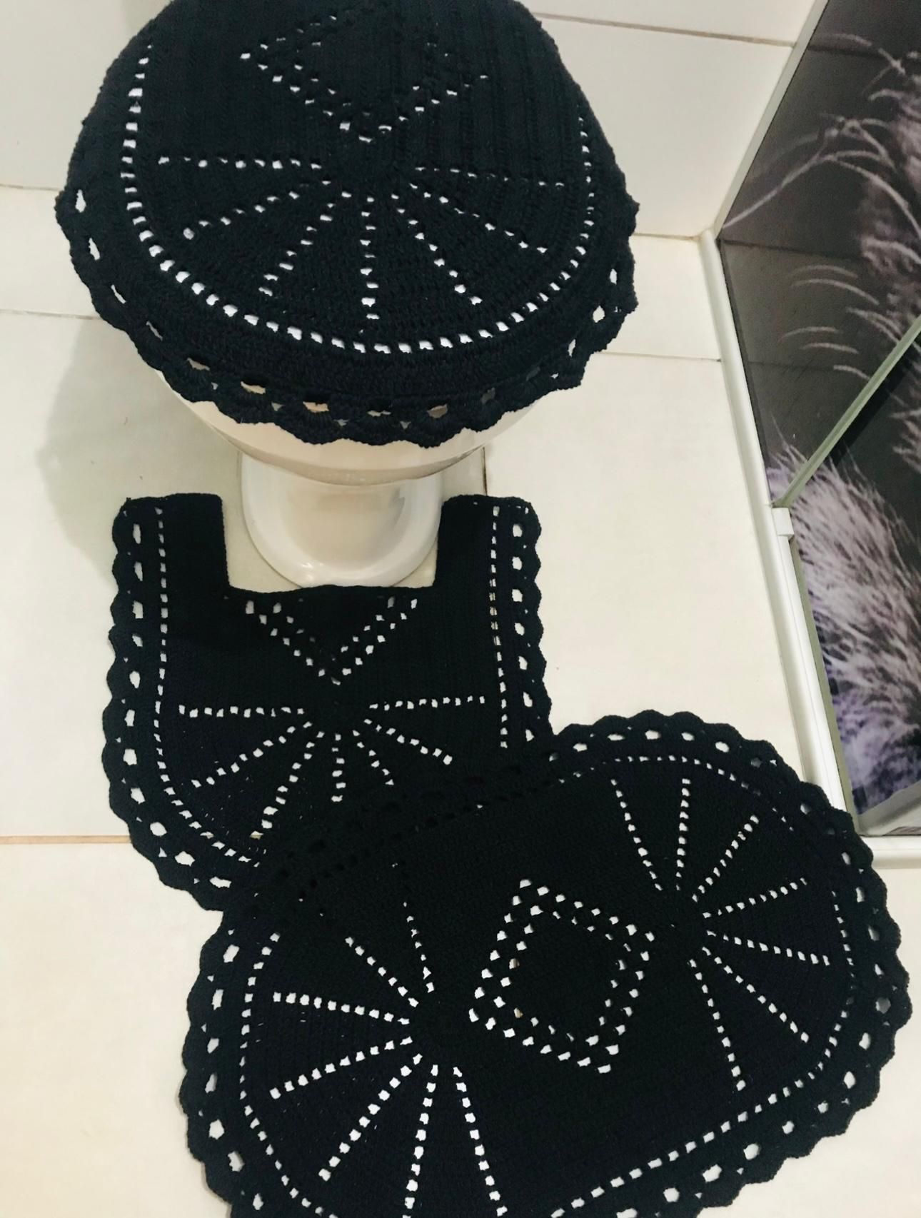 Black crocheted toilet seat cover and matching rug set with white stitching and scalloped edges.