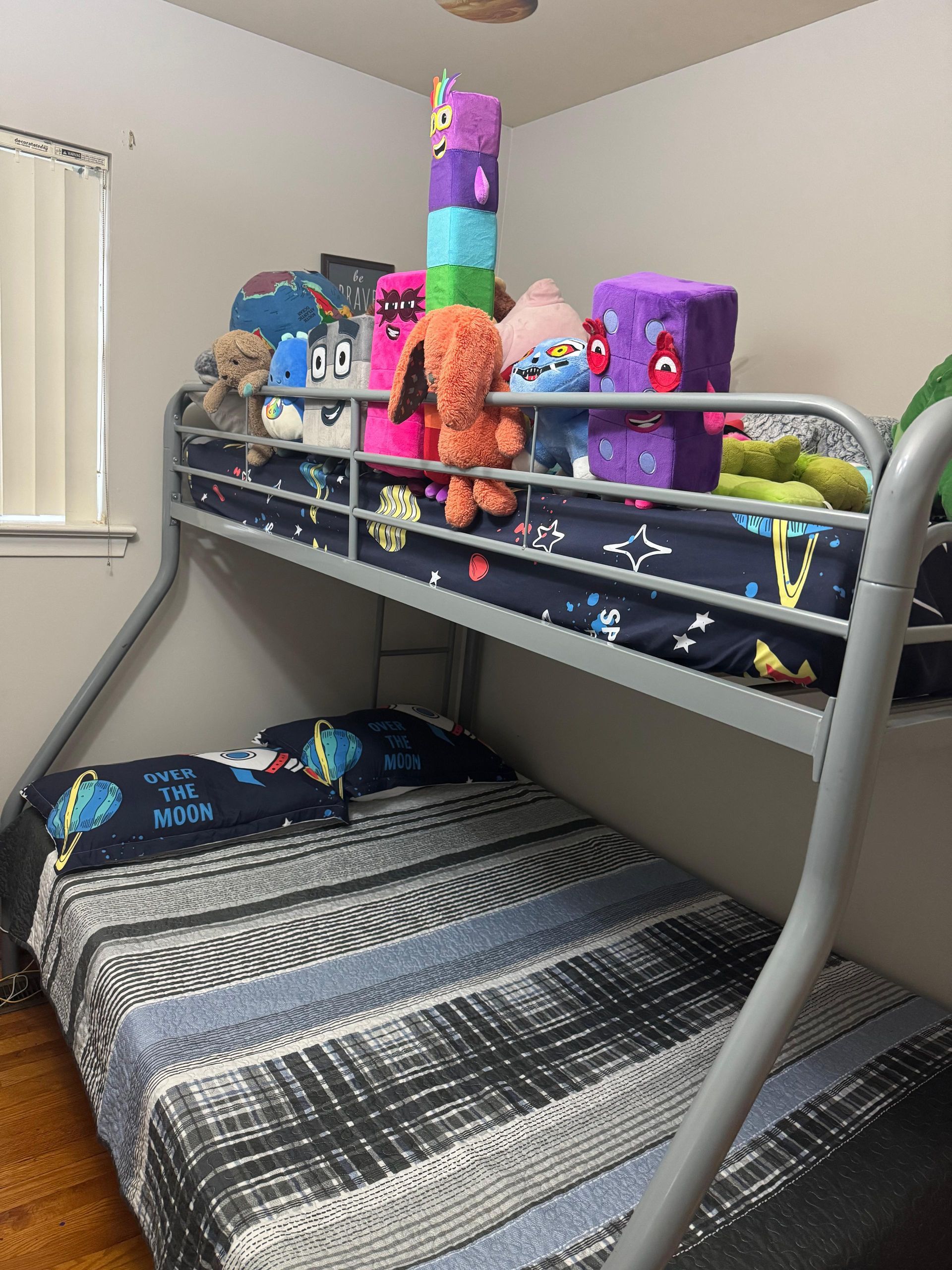 Bunk bed in a small bedroom, top bunk covered with stuffed animals and colorful toys. Bunk bed in a small bedroom, top bunk covered with stuffed animals and colorful toys.