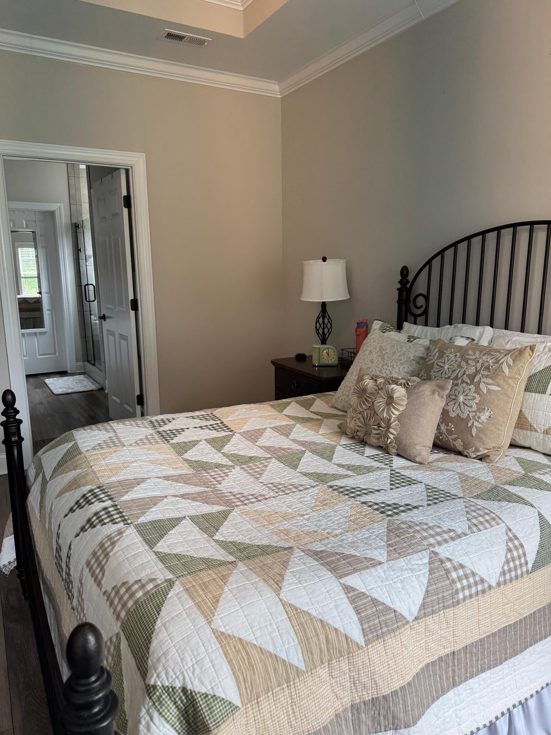 Bedroom with a quilted bed, striped headboard, bedside lamp, and mirrored closet doors. Bedroom with a quilted bed, striped headboard, bedside lamp, and mirrored closet doors.