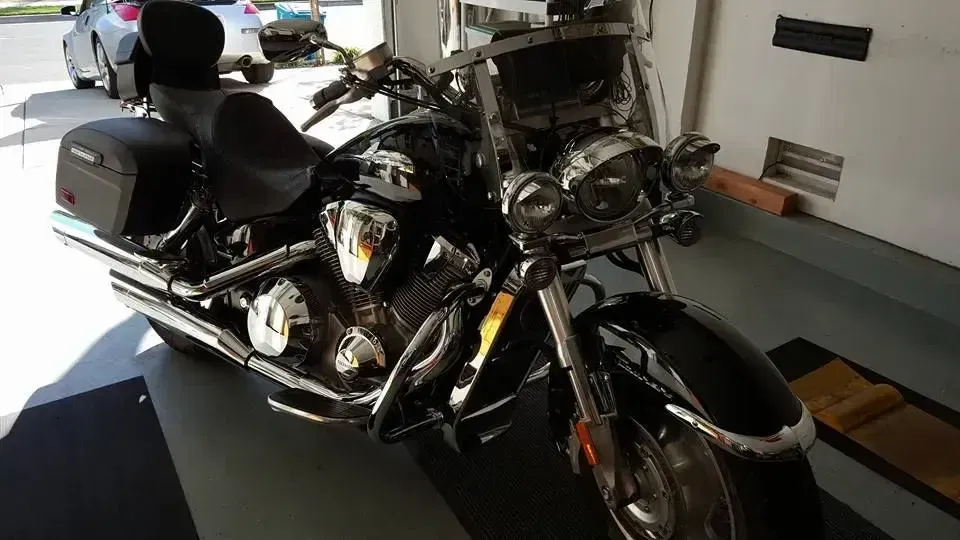 Chrome cruiser motorcycle parked in a garage, with saddlebags and a windshield