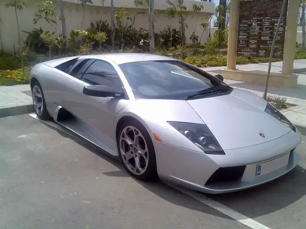 Silver sports car parked outdoors in a lot, front view at an angle