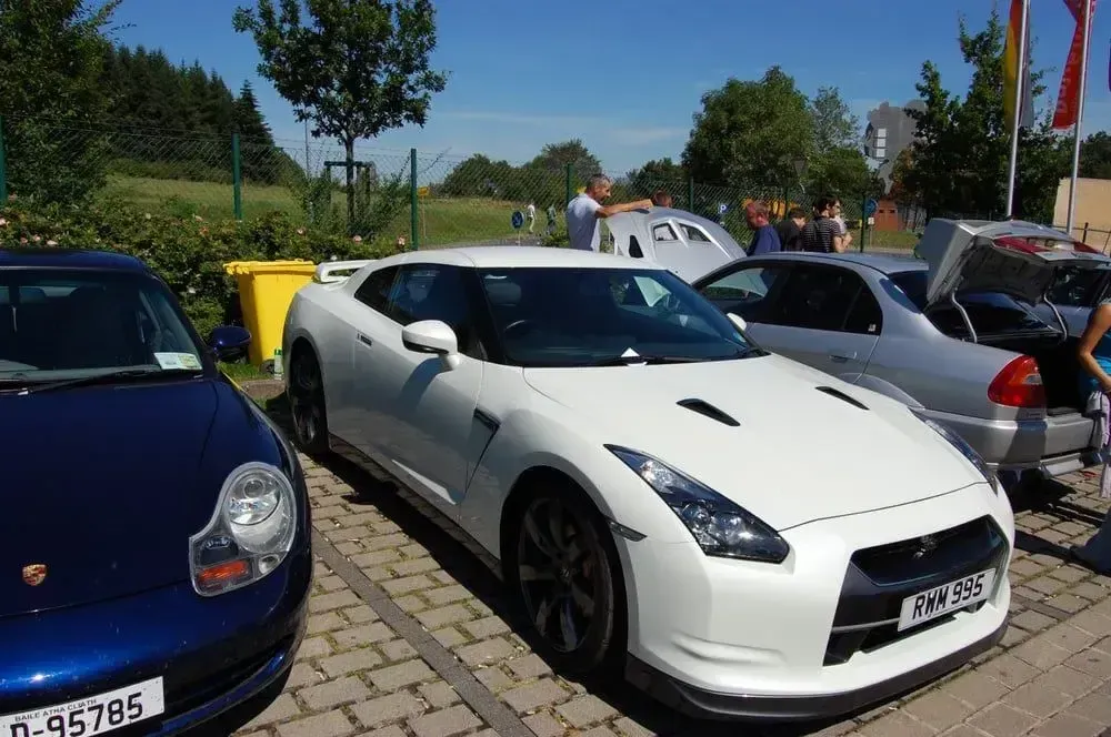 White sports car parked among other cars at an outdoor lot on a sunny day