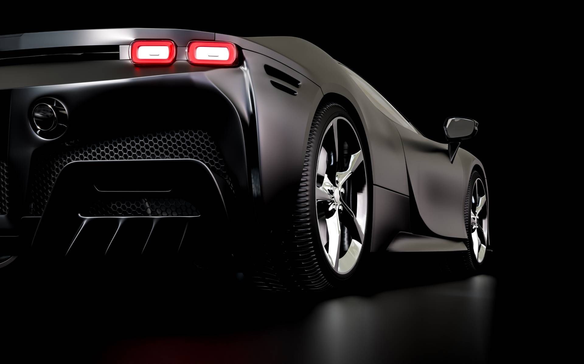 Rear view of a sleek black sports car with glowing red taillights on a dark studio background