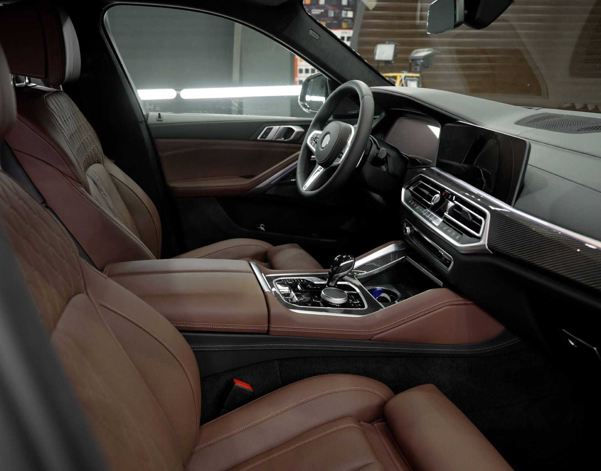 Luxury car interior with brown leather seats, dashboard, and steering wheel viewed from the passenger side