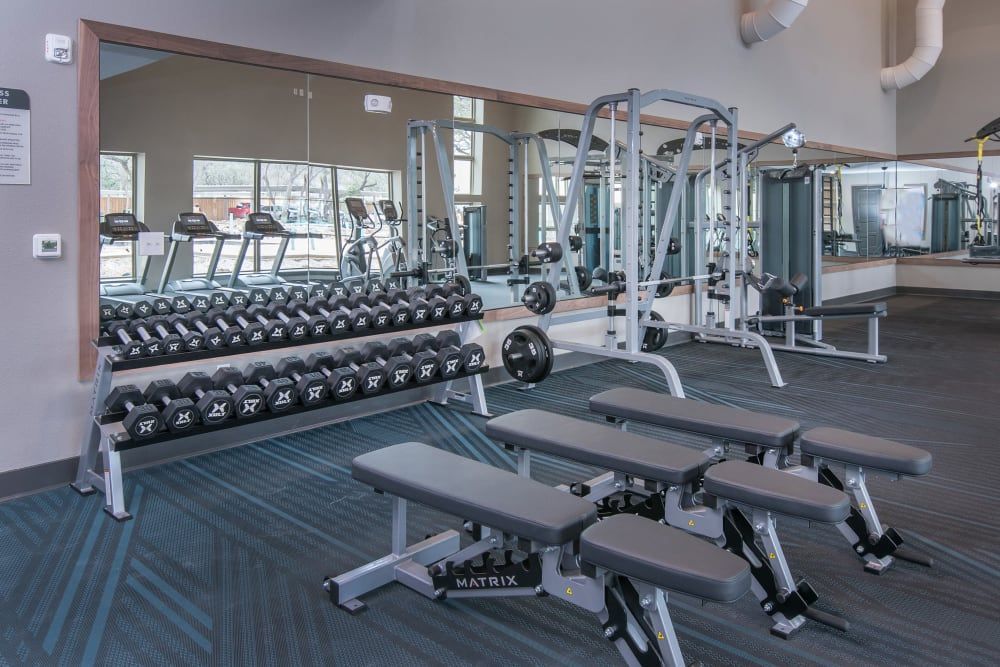 A gym filled with lots of dumbbells and benches at Marquis Dominion in San Antonio, TX.