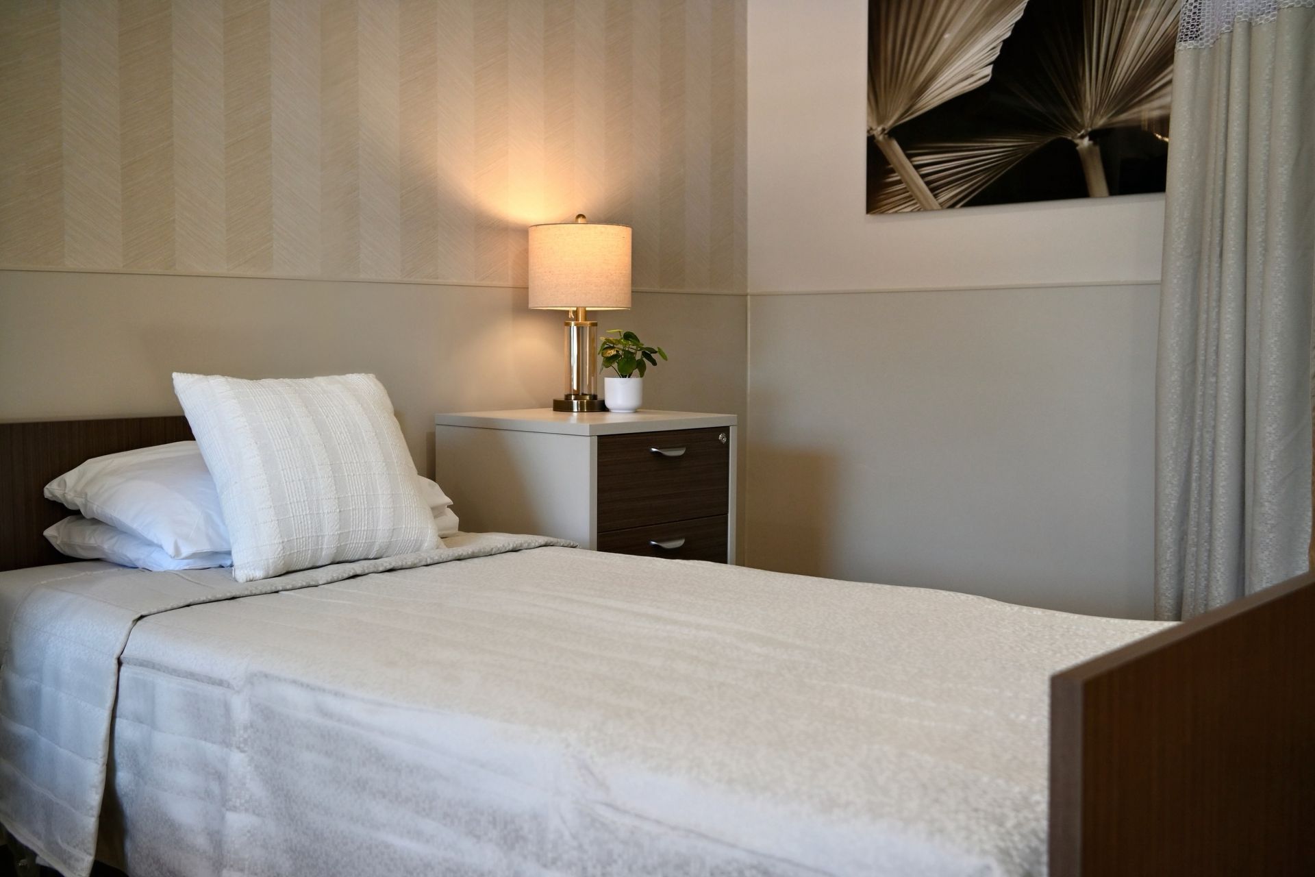 Neat bedroom with a made bed, bedside lamp, and curtains in soft neutral tones