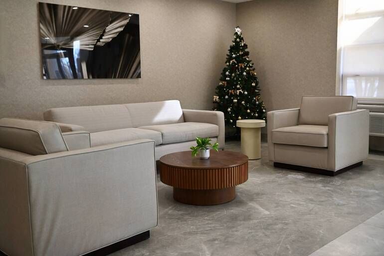 Modern living room with beige sofas, armchair, coffee table, and a decorated Christmas tree