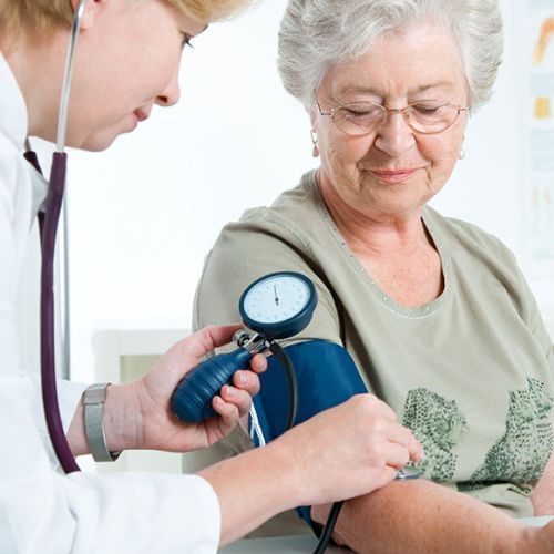 Doctor checking elderly woman's blood pressure with a cuff and gauge
