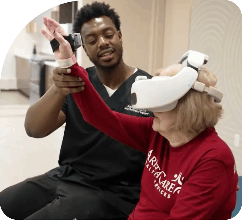 Man in black scrubs helping a seated woman wear a white VR headset in a bright room