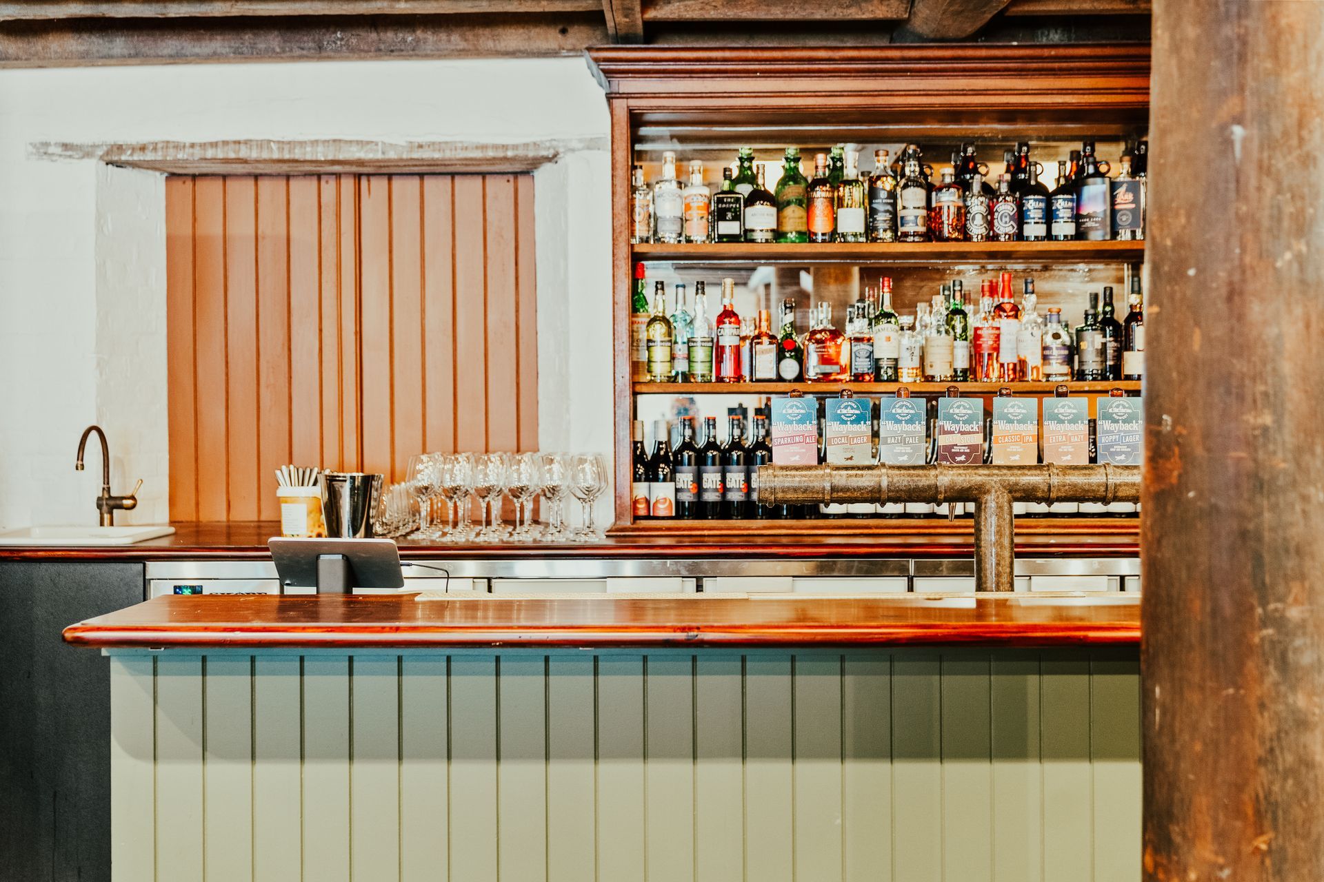 Bar with liquor bottles on shelves, wooden counter, and a wood-paneled wall.