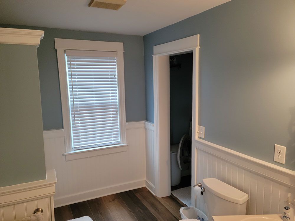 A painted bathroom with new trim and moulding, a toilet , sink , and window.