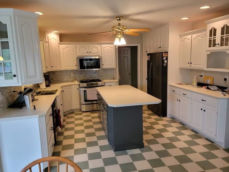 A kitchen with painted white cabinets and a checkered tile floor