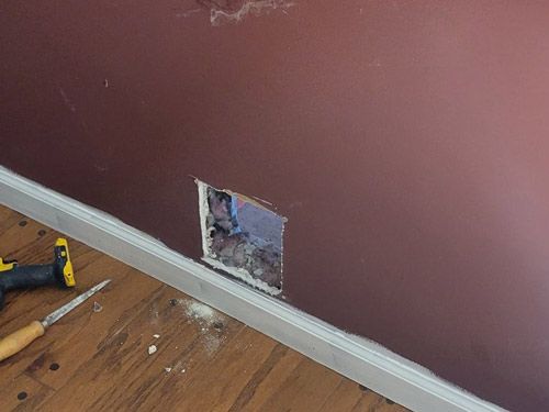 A hole in a wall is being filled with a drill.