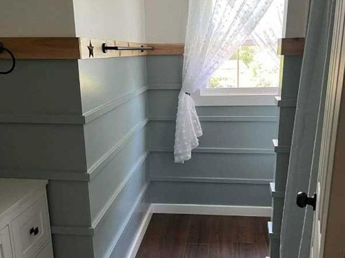 A bathroom with a white door and a shower that had wallpaper removed.