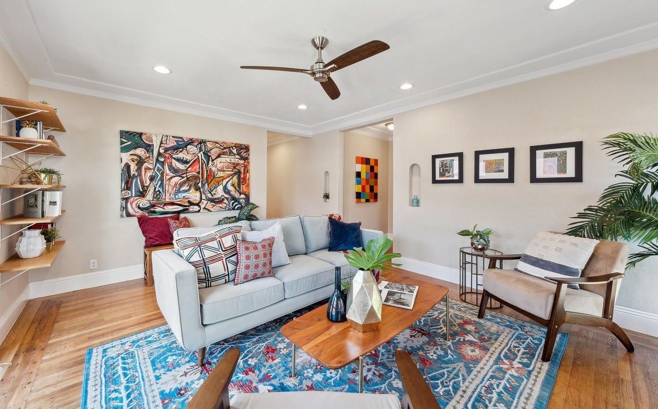 A living room with a couch , chairs , and a ceiling fan.