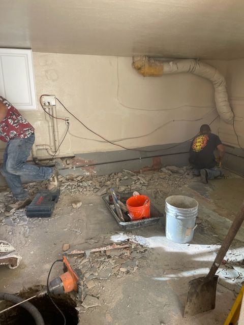 Two men are working on the floor of a garage.