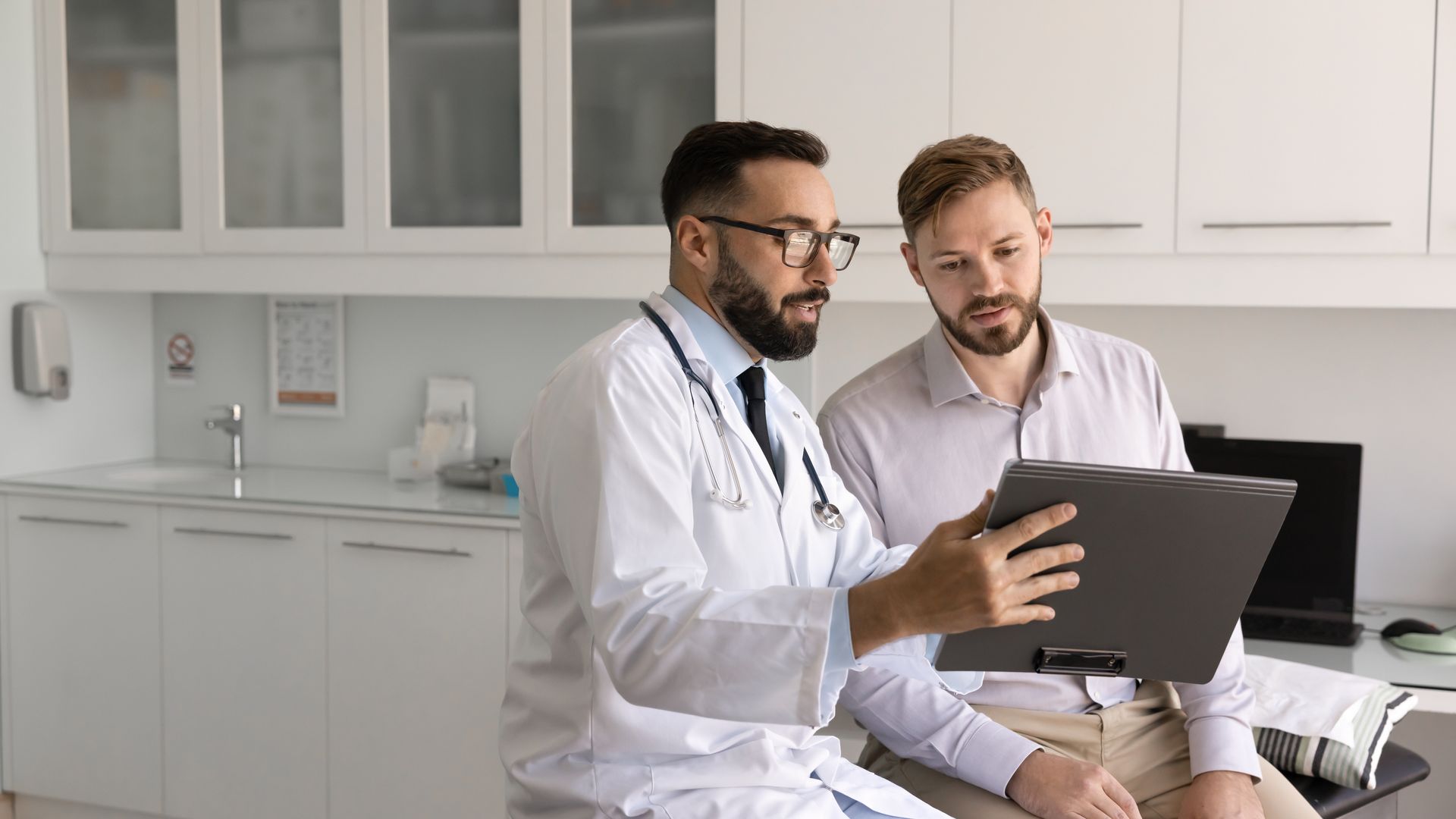 Doctor showing a laptop to a patient in a bright clinic office Doctor showing a laptop to a patient in a bright clinic office