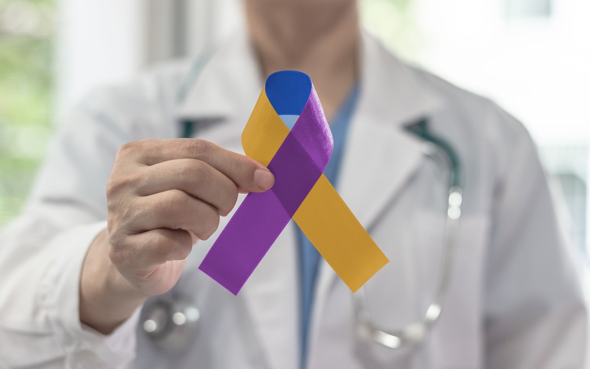 Doctor holding a yellow and purple awareness ribbon Doctor holding a yellow and purple awareness ribbon