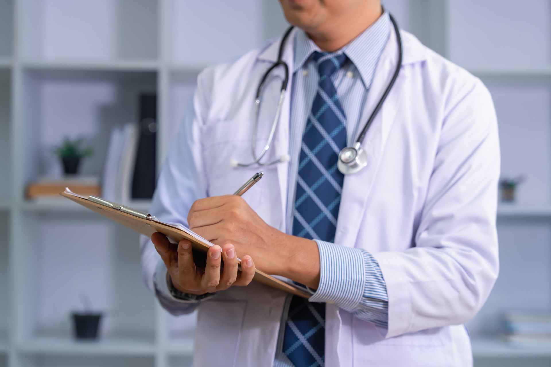 Doctor holding a clipboard and writing notes in a clinic office Doctor holding a clipboard and writing notes in a clinic office