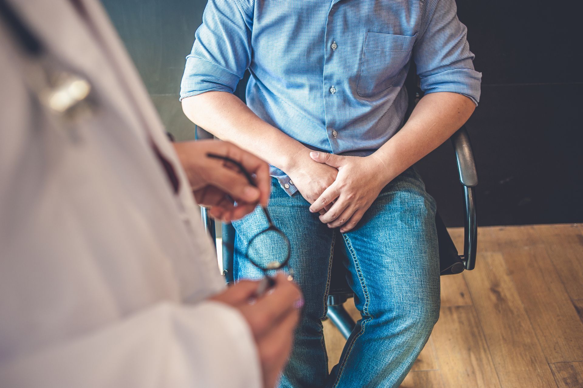 Doctor holding a stethoscope near a seated patient in a blue striped shirt and jeans. Doctor holding a stethoscope near a seated patient in a blue striped shirt and jeans.