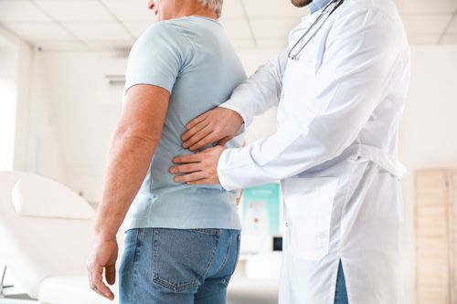 Doctor examining a patient’s back in a bright clinic room Doctor examining a patient’s back in a bright clinic room