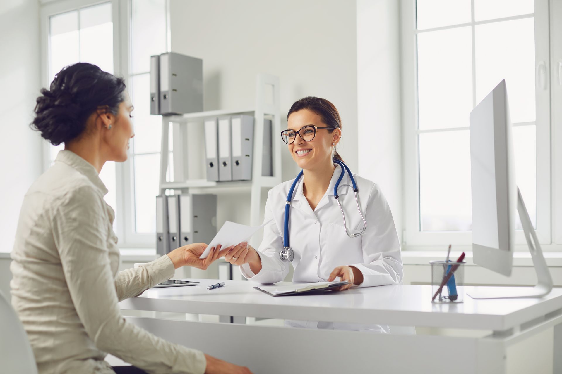 Doctor smiling and shaking hands with a patient at a bright clinic desk Doctor smiling and shaking hands with a patient at a bright clinic desk
