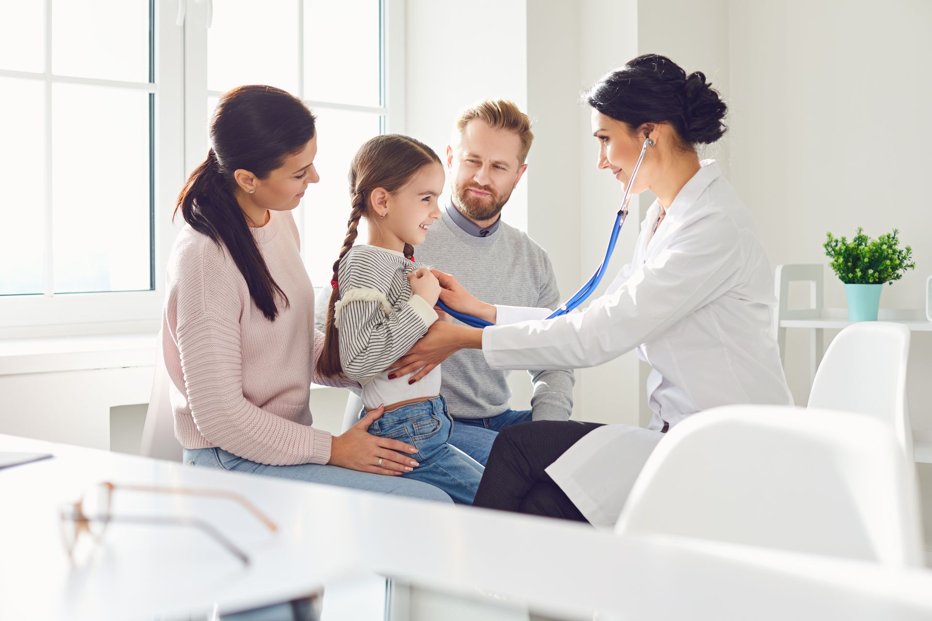Doctor examining a child with parents in a bright clinic room