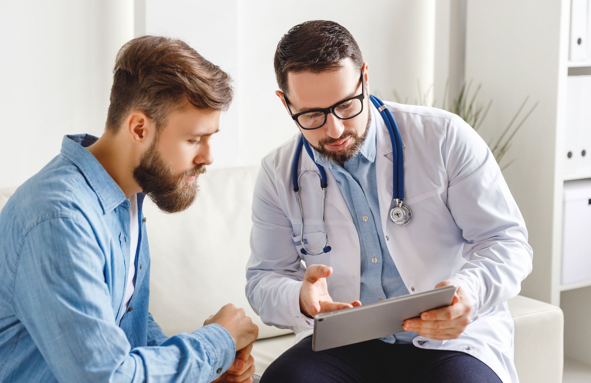 Doctor discussing a tablet with a seated patient in a bright clinic office Doctor discussing a tablet with a seated patient in a bright clinic office