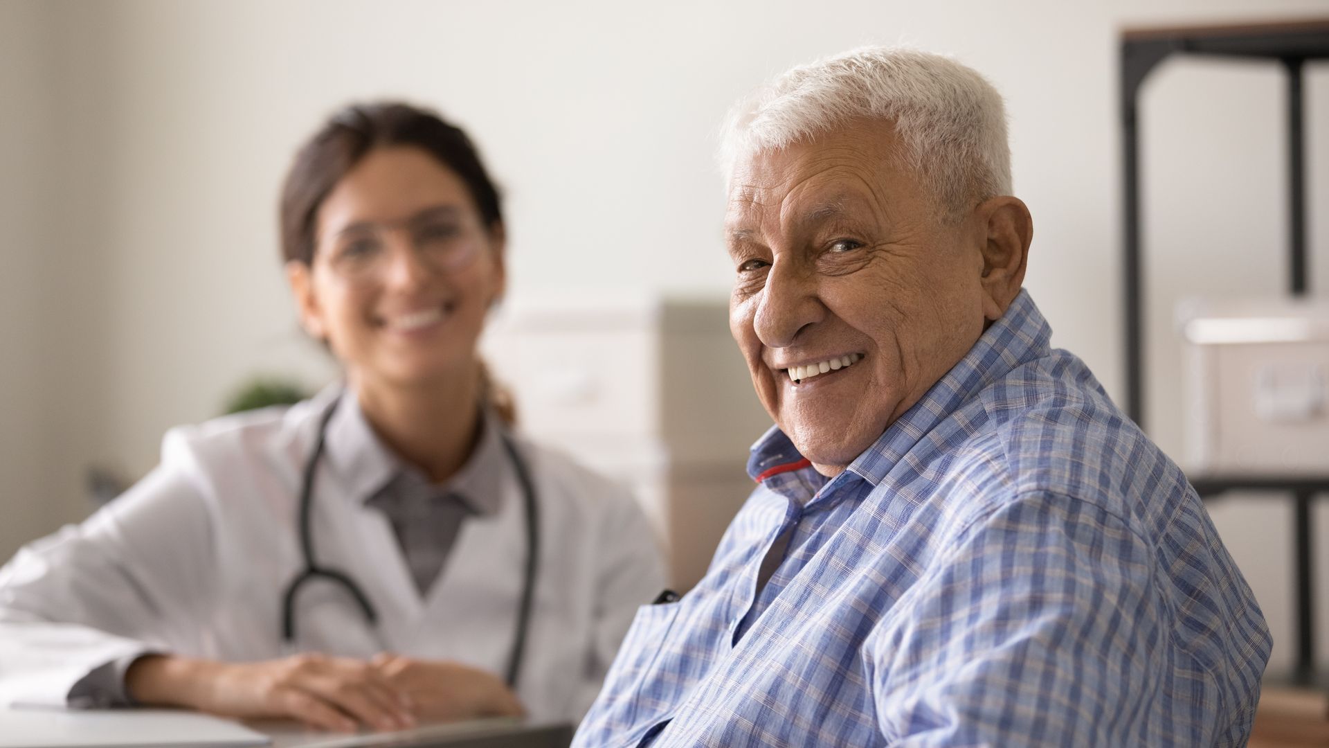 Smiling patient with doctor in a clinic office, both seated at a desk. Smiling patient with doctor in a clinic office, both seated at a desk.