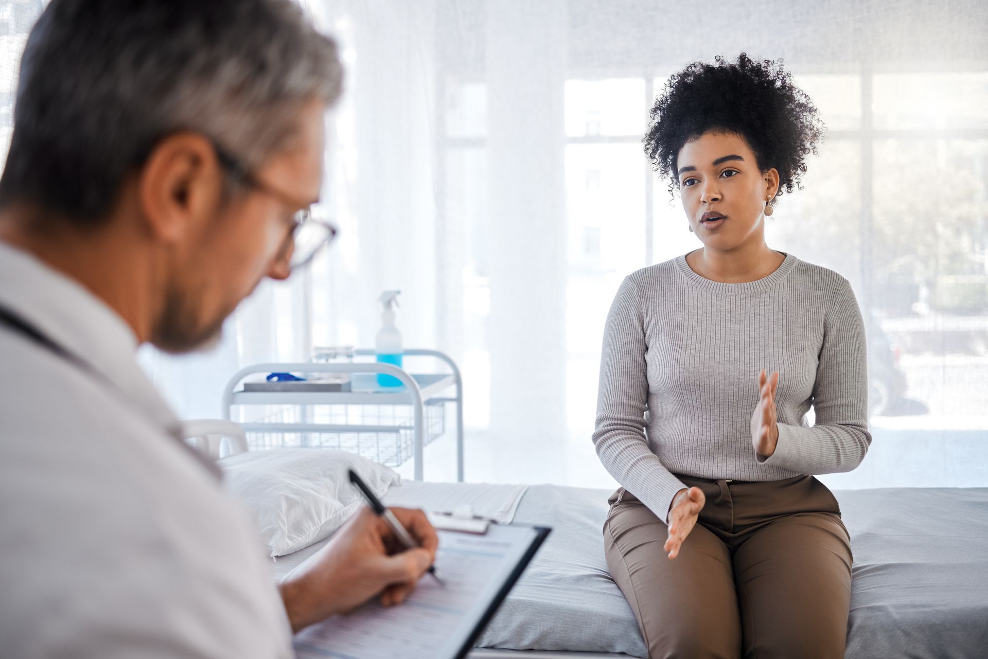 Patient speaking with doctor during a consultation in a bright exam room Patient speaking with doctor during a consultation in a bright exam room