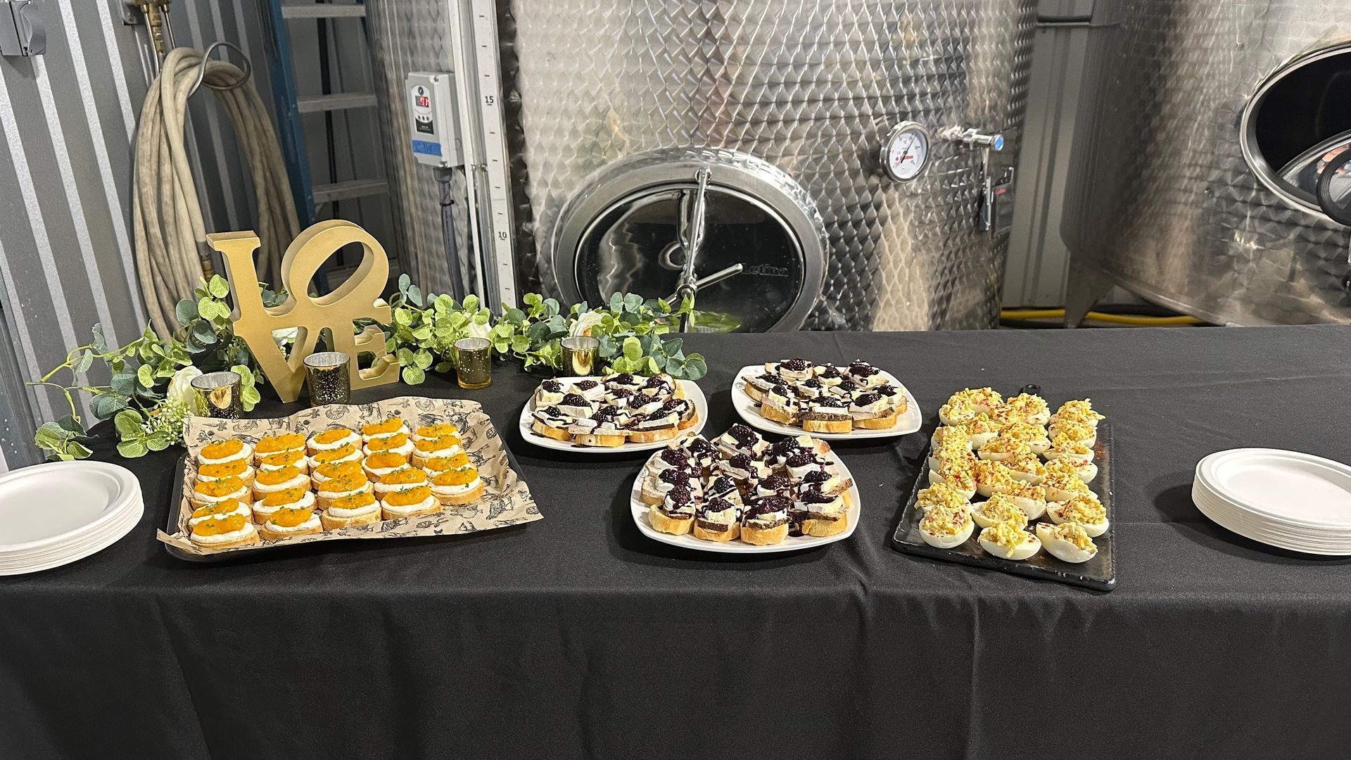 A table with appetizers in front of wine vats. 