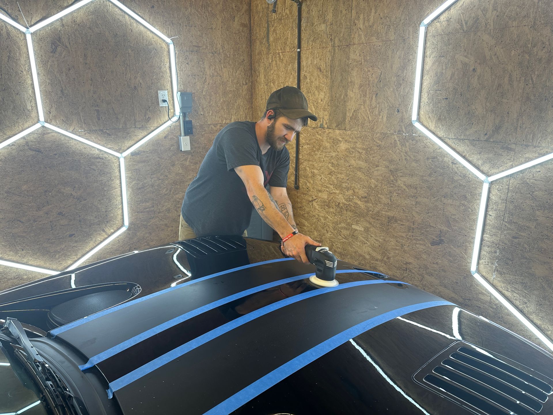 a man is polishing the roof of a black car in a garage .