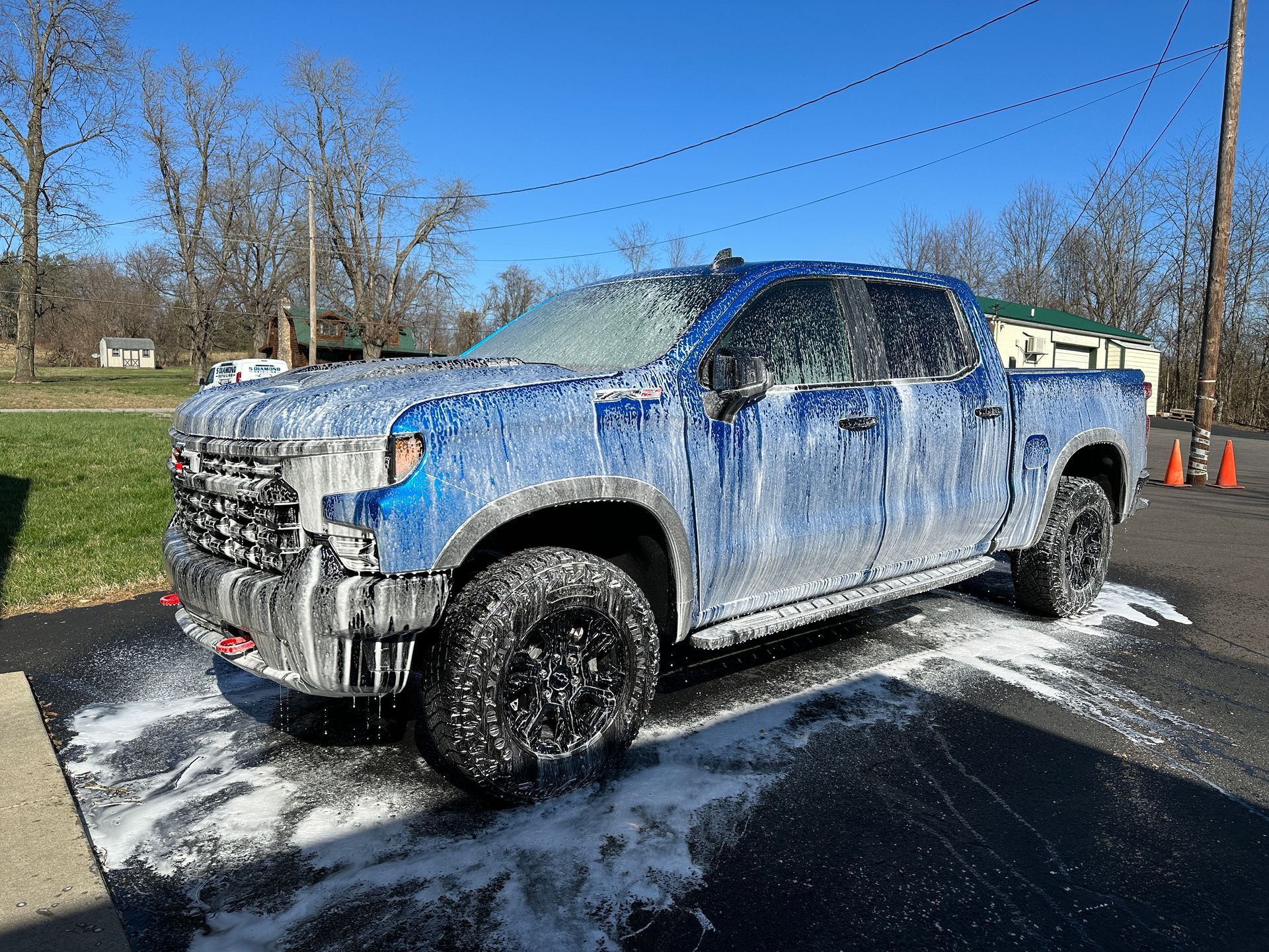 a blue truck is covered in foam in a parking lot .
