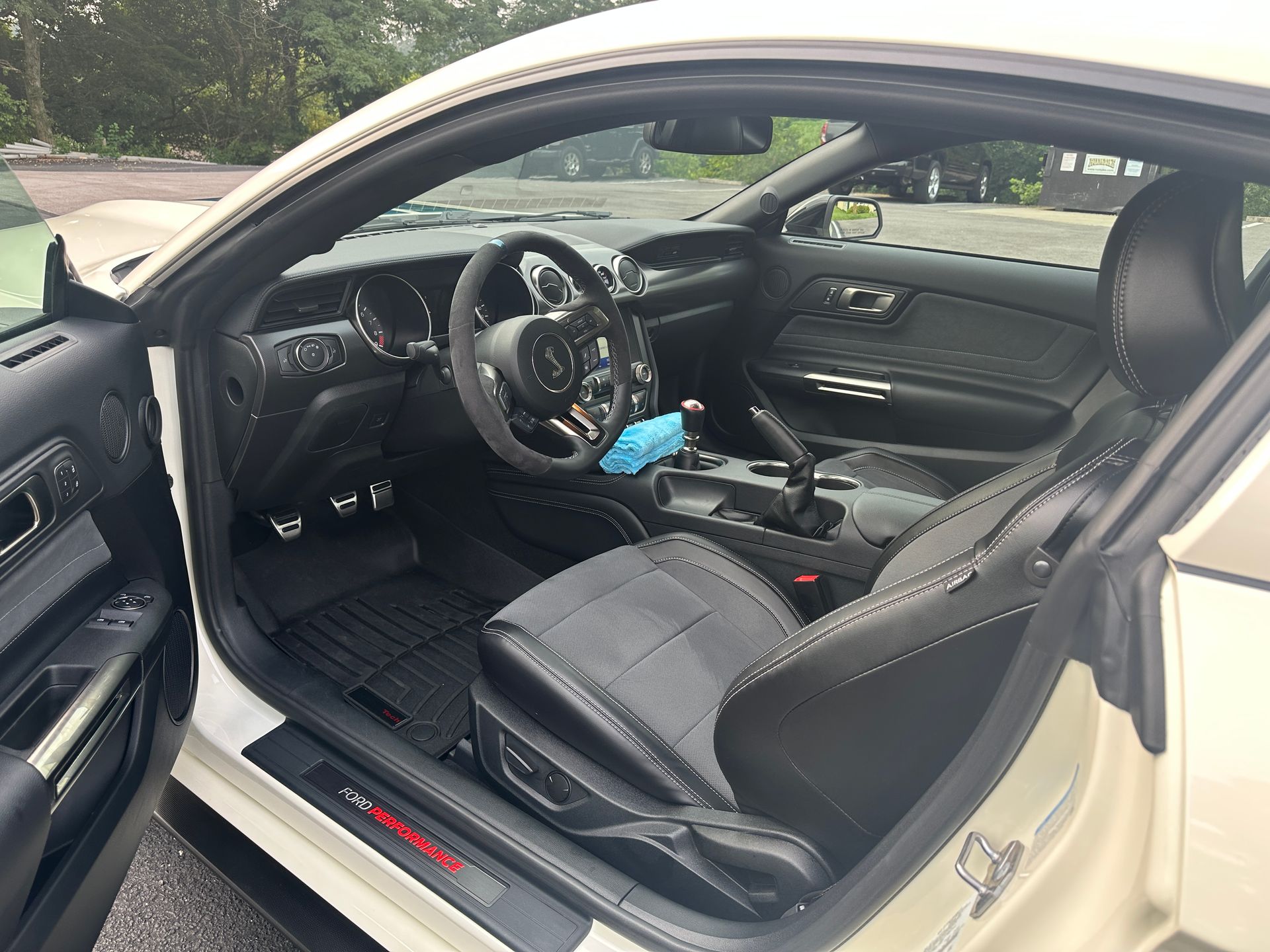 the inside of a white ford mustang with the door open