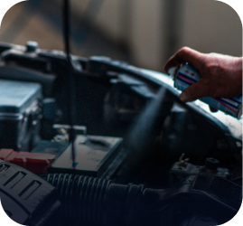 A hand sprays cleaning product into the open engine bay of a car | Ames Automotive STC