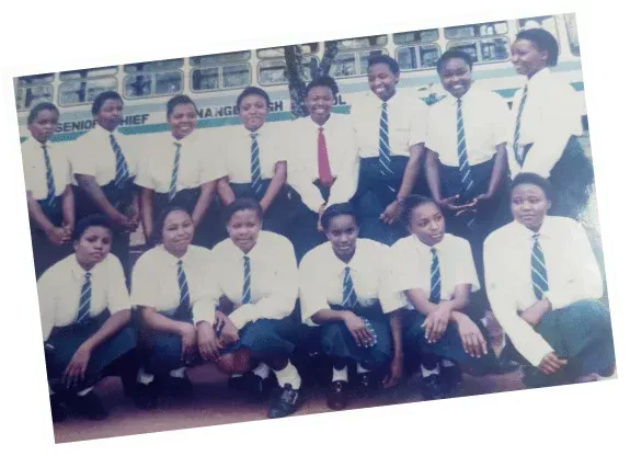 Group of students in white shirts and ties posing outdoors in two rows
