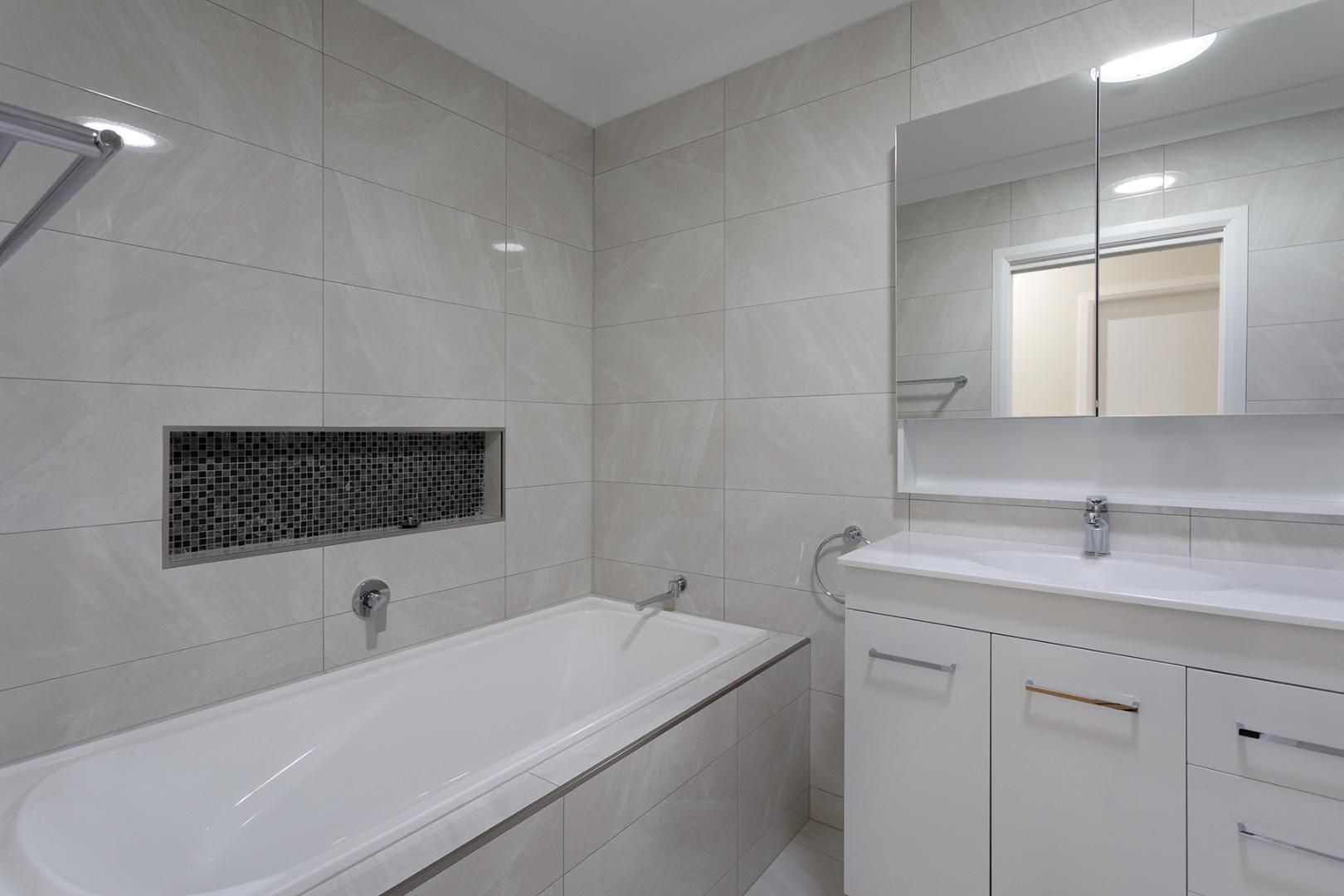 A Bathroom With a Bathtub, Sink, Mirror and Shower — Kareela Constructions In Tamworth, NSW