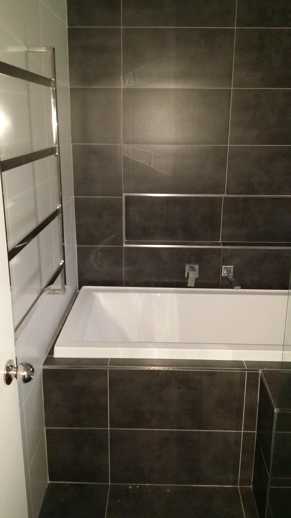 There is a Bathtub in the Bathroom With Black Tiles — Kareela Constructions In Tamworth, NSW
