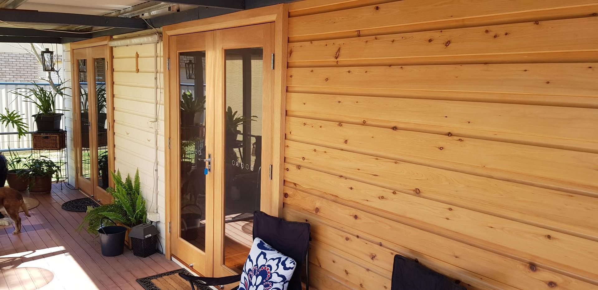 A Wooden Porch With a Chair, Table and Plants — Kareela Constructions In Tamworth, NSW