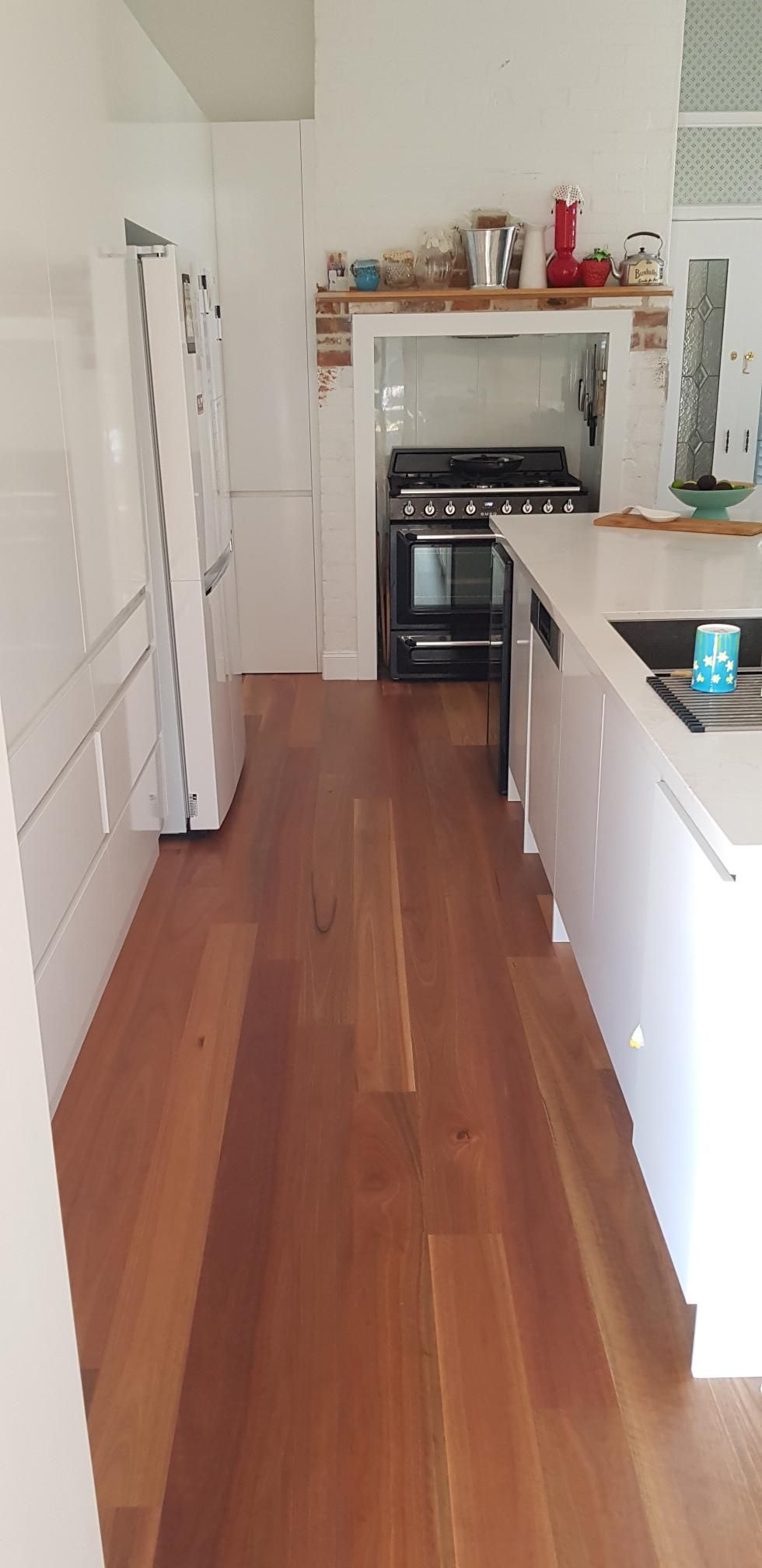 A Kitchen With Hardwood Floors, White Cabinets, a Stove and a Refrigerator — Kareela Constructions In Tamworth, NSW