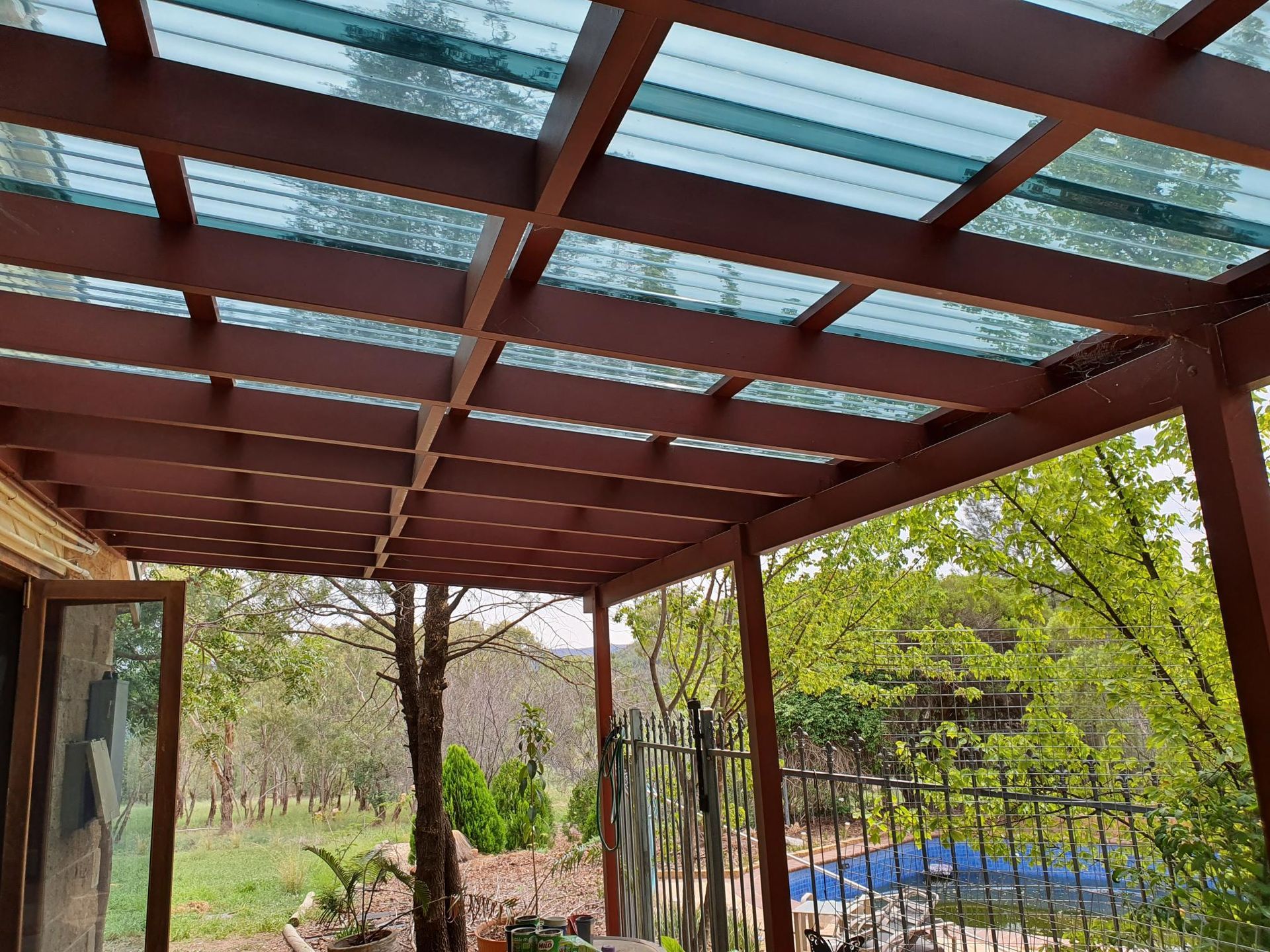 A Wooden Pergola With a Clear Glass Roof — Kareela Constructions In Tamworth, NSW