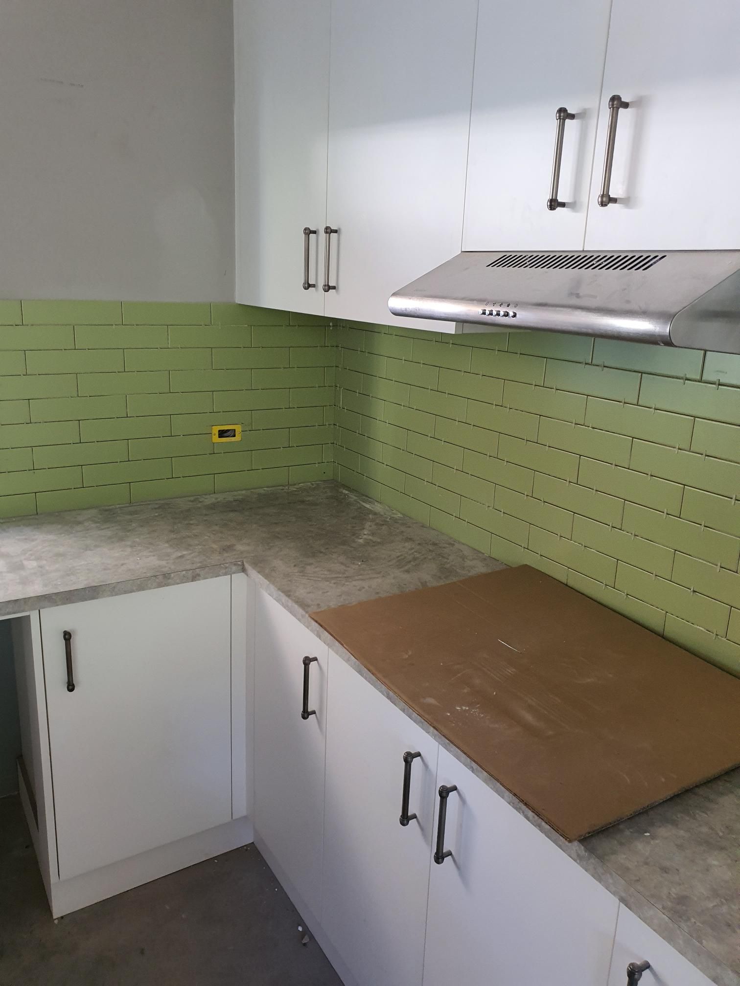 A Kitchen With Green Brick Walls and White Cabinets — Kareela Constructions In Tamworth, NSW
