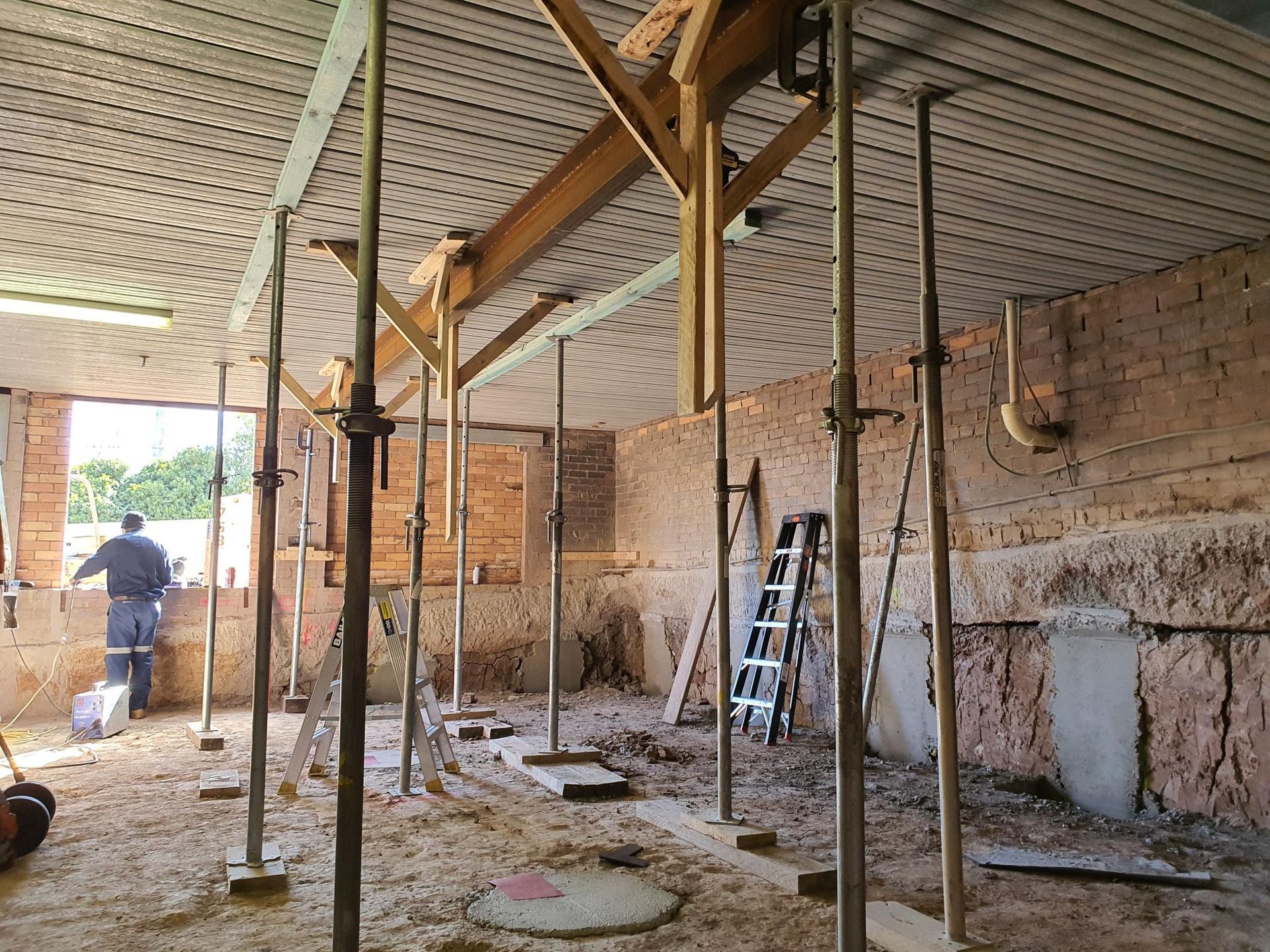 A Man is Standing in a Room With Scaffolding and a Ladder — Kareela Constructions In Tamworth, NSW