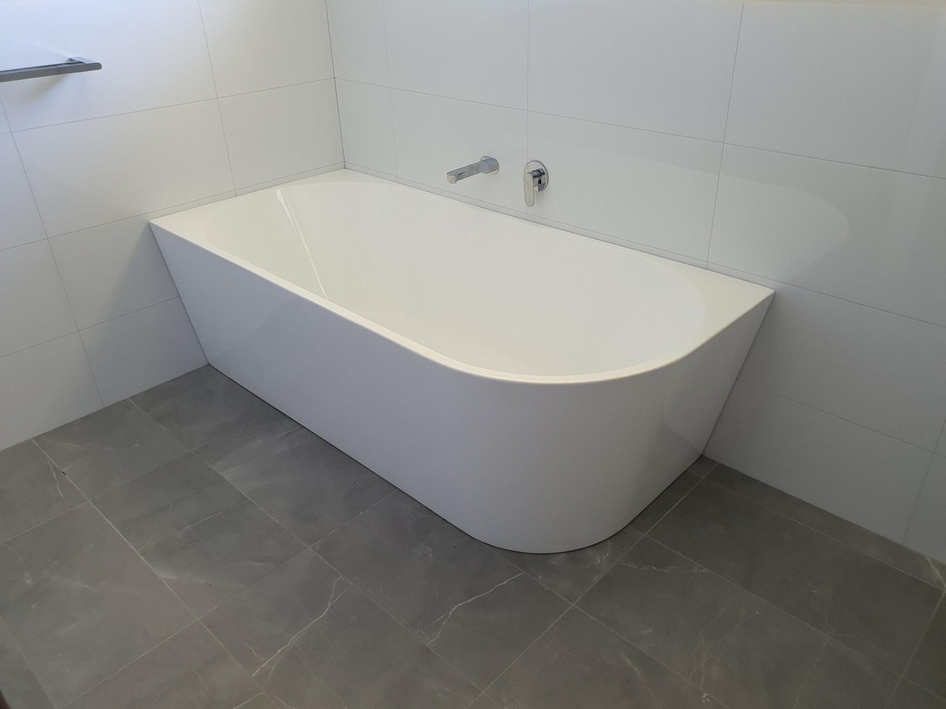 A White Bathtub is Sitting on a Tiled Floor in a Bathroom — Kareela Constructions In Tamworth, NSW