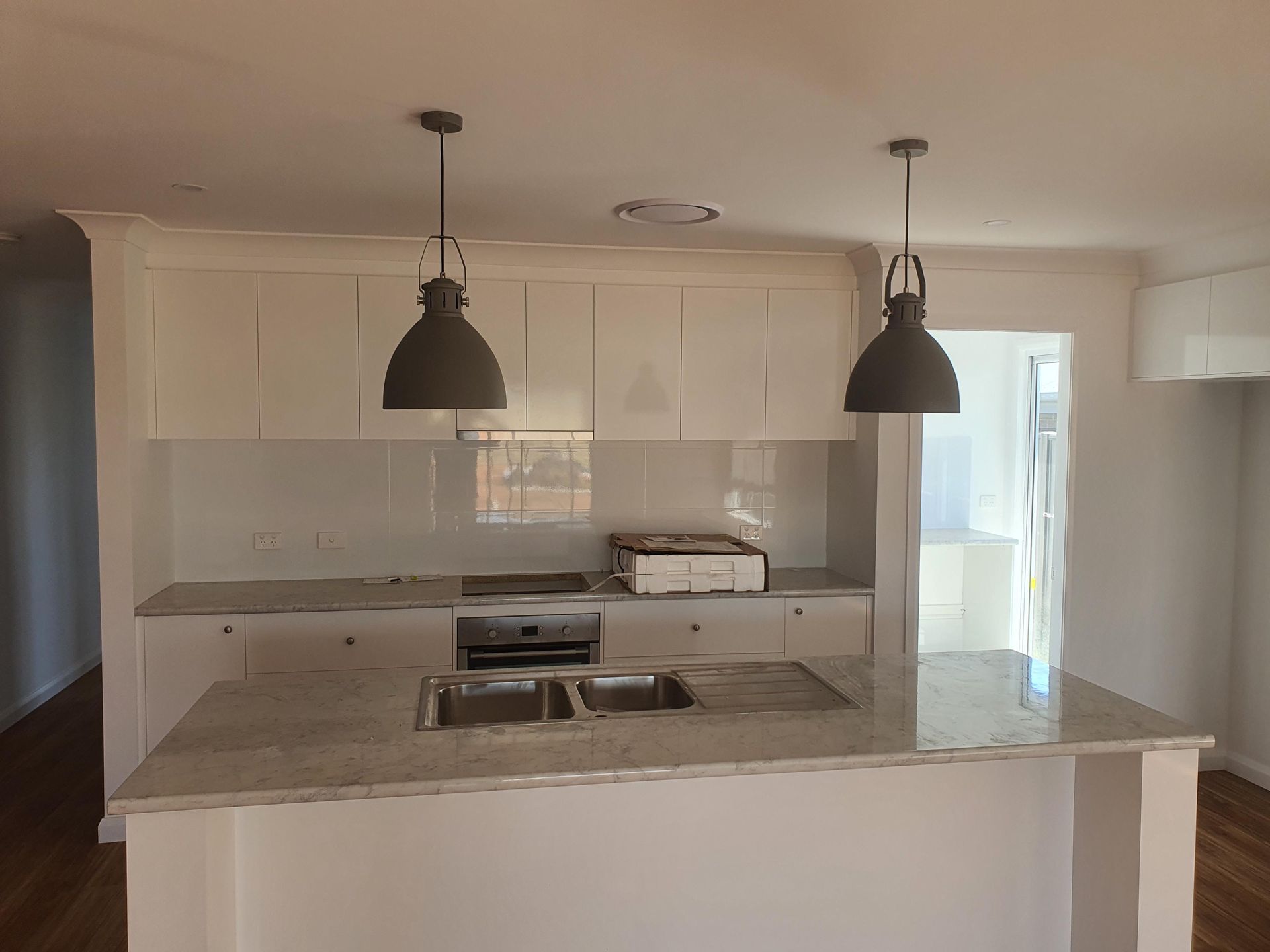 A Kitchen With White Cabinets, a Sink, a Stove and Two Pendant Lights — Kareela Constructions In Tamworth, NSW