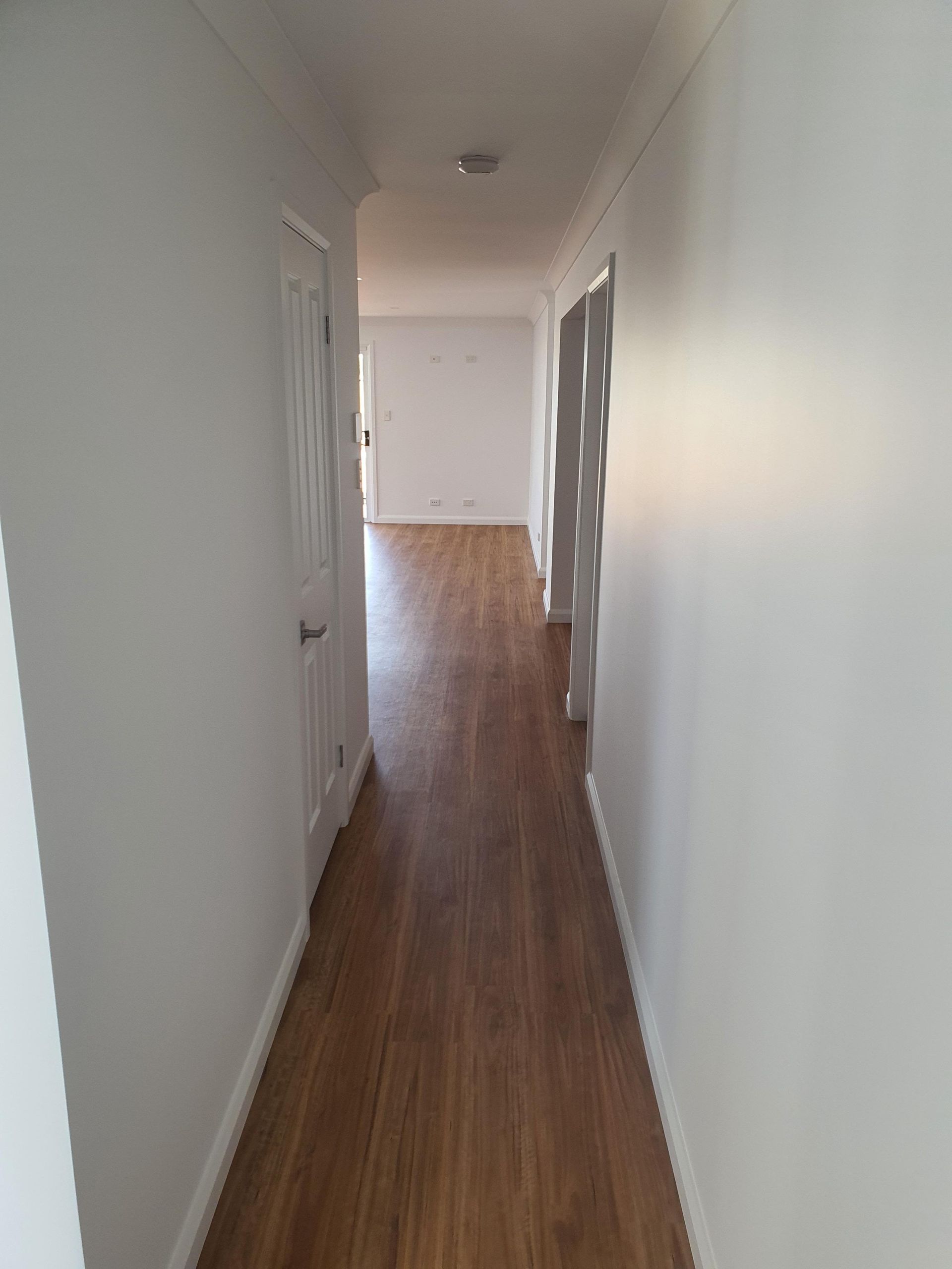 A Long Hallway With Wooden Floors and White Walls — Kareela Constructions In Tamworth, NSW